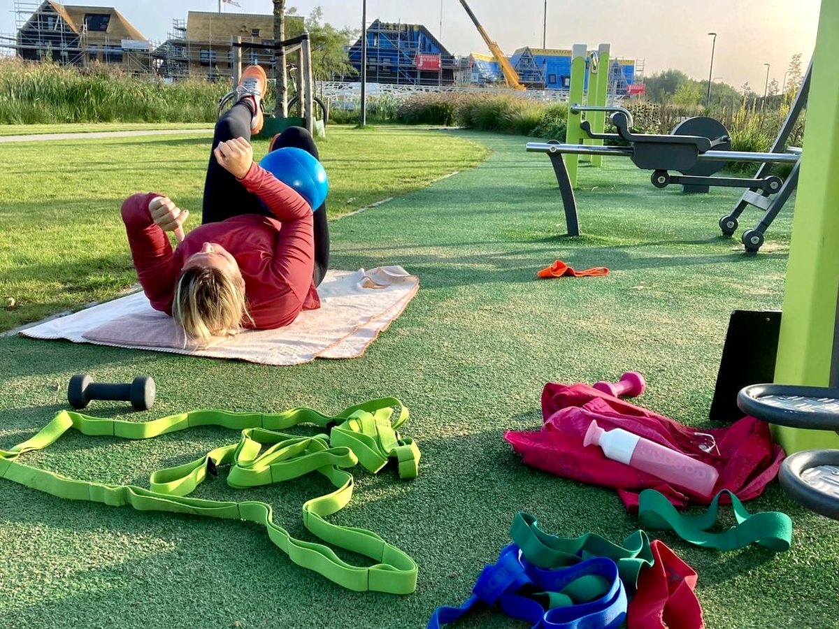 Twee mensen trainen op matten bij een buitenfitness
